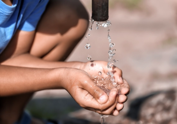 Child drinking clean water from tap supplied by a safe water system